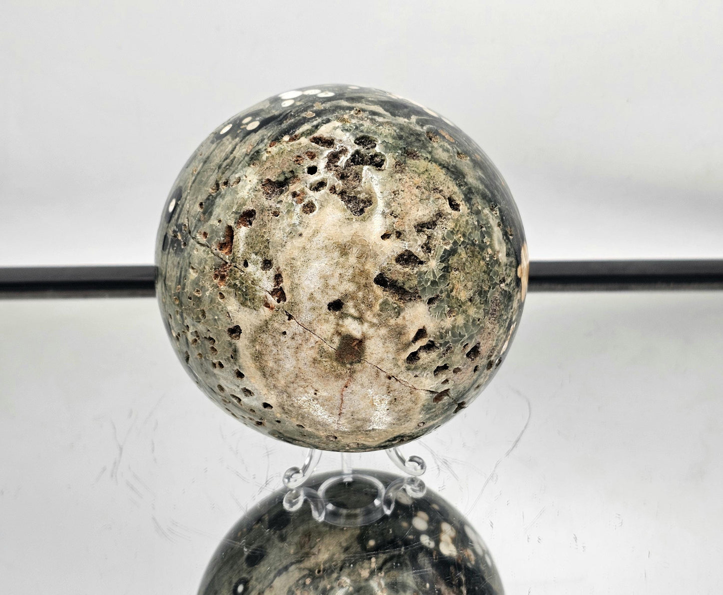 Large Ocean Jasper crystal sphere with orbital patterns and natural cavities.